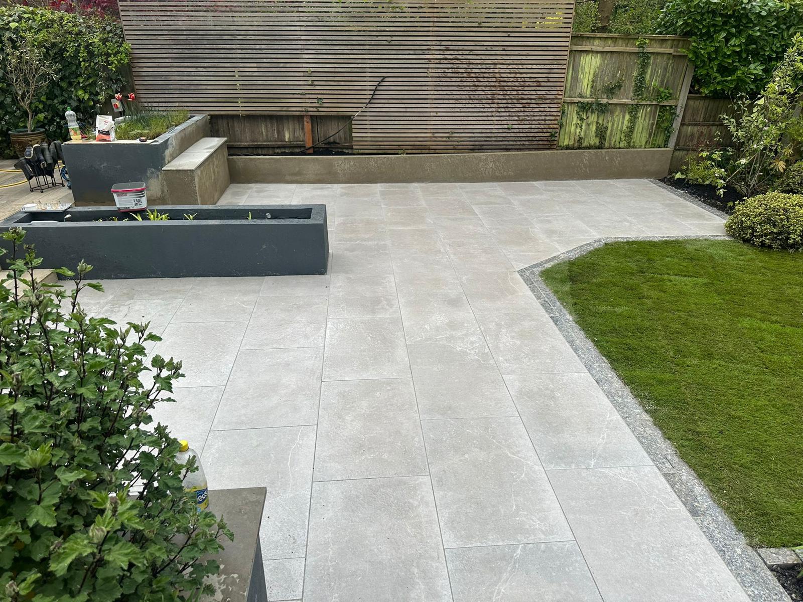 Patios Bromley Grey paving following a planted border beside a lawn